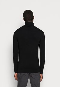 Svart polotröja med långa ärmar, rörstruktur och en figurnära design. Inga synliga mönster eller detaljer. Bakvy.