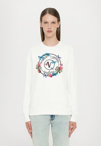 Felpa bianca con una grafica rotonda di fiori e farfalle, con testo decorativo. Tessuto morbido, colletto rotondo e orlo a coste.