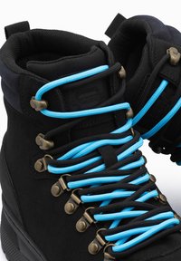 Botas de senderismo negras con cordones azules y negros, ojales de metal, cuello acolchado y material texturizado, con puntera y talón reforzados.