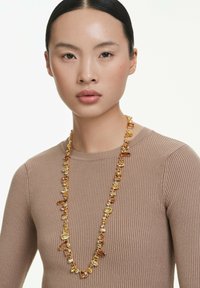 Collana in tonalità d'oro con vari grani sfaccettati e lisci, caratterizzata da sfumature di giallo e ambra in forme rettangolari e ovali.