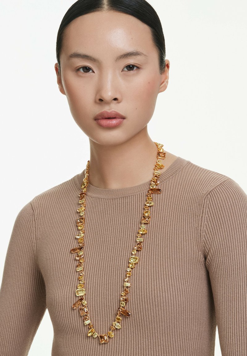 Collana in tonalità d'oro con vari grani sfaccettati e lisci, caratterizzata da sfumature di giallo e ambra in forme rettangolari e ovali.