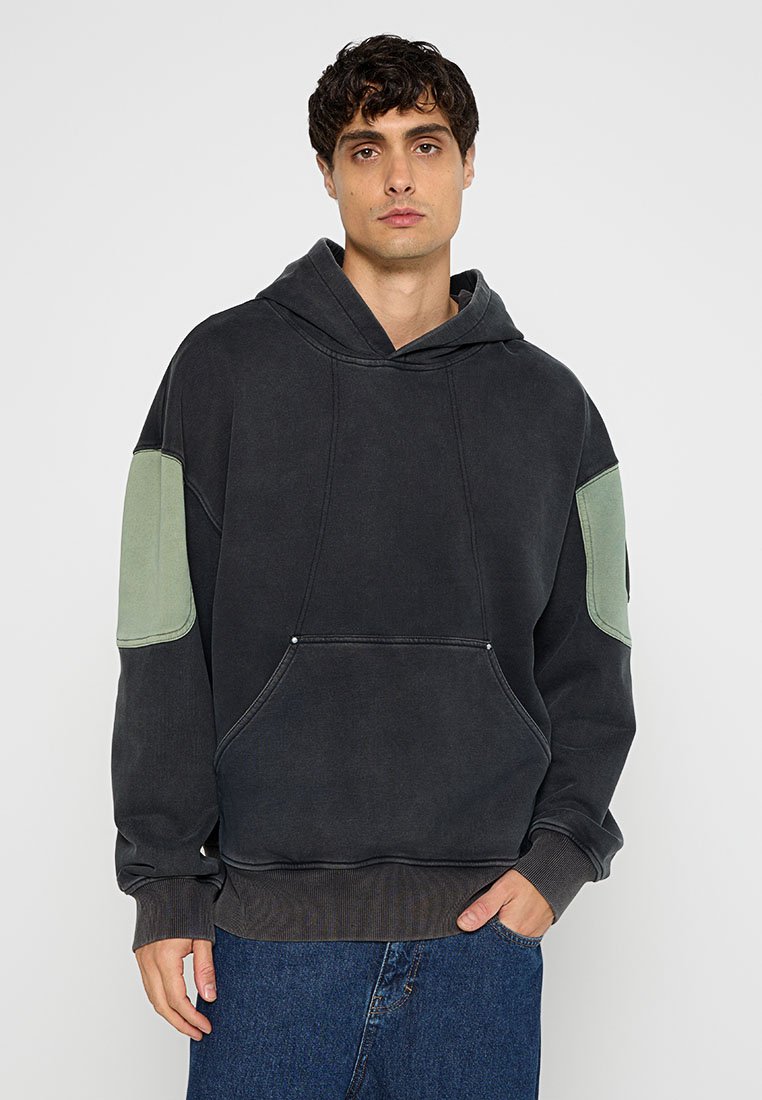 Dunkelgrauer Hoodie mit grünen Schulterpatches, Kordelzugkapuze, Fronttasche, gerippte Bündchen und Saum. Weicher Stoff mit lockerer Passform.