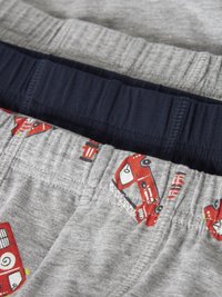 Τρία ζευγάρια παιδικά παντελόνια με ελαστική μέση, δύο σε μονόχρωμες αποχρώσεις (γκρι και ναυτικό μπλε), και ένα γκρι με κόκκινα σχέδια πυροσβεστικού οχήματος και πυροσβεστικού κρουνου.