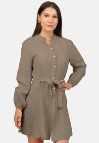 Abito beige con bottoni, realizzato in un tessuto testurizzato, maniche lunghe e un dettaglio in vita legato. Presenta un colletto classico e un orlo arrotondato.