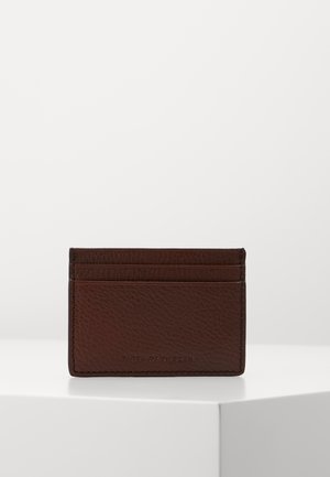 Brown leather cardholder with a textured finish, featuring four card slots and a debossed logo on the front. Compact rectangular design.