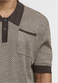 Pánská polokošile s krátkým rukávem s texturovaným vzorem houndstooth v béžové a hnědé barvě, vybavená temně hnědým límečkem a kapsou na prsou.