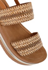 Beige wedge sandal with two woven, braided straps, adorned with narrow rhinestone accents, and a smooth tan footbed.