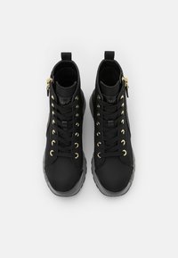 Sneaker alte nere realizzate in tessuto, con occhielli, lacci e cerniera laterale dorati. Suola in gomma con accenti testurizzati.