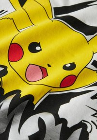 Yellow Pikachu character graphic on fabric, featuring red cheeks, large eyes, and a surprised expression against a black and white background.