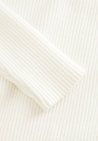 Tissu blanc côtelé présentant une texture douce et une finition lisse, mettant en avant un gros plan sur le matériau et les détails du design.