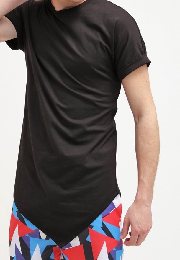Camiseta negra de manga corta con cuello redondo y dobladillo curvado, combinada con pantalones cortos de patrón geométrico multicolor, que presentan rojo, azul y blanco.