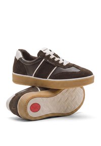 Paire de baskets marron et blanches décontractées avec semelles en gomme, lacets blancs et une étiquette rouge "Tamaris Comfort" sur la semelle.