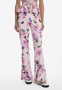 Pantaloni rosa a zampa d'elefante con un vivace pattern floreale e di farfalle. Realizzati in tessuto morbido, presentano una texture liscia e una vestibilità comoda.