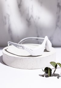 Białe plastikowe okulary z przezroczystymi zausznikami, o kanciastym designie. Wytłoczone logo "STYLPRO" po boku. Gładkie, matowe wykończenie.