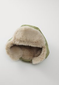 Chapeau à coque extérieure verte avec une doublure en fausse fourrure beige, présentant un design arrondi et un large rebord duveteux. Texture lisse et intérieur doux.