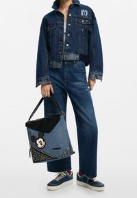 Farkkutakki, jossa on Mikki Hiiri -kirjonta, yhdistettynä löysiin farkkuihin. Musta ja sininen laukku, jossa on Mikki-kuvio ja teksturoidut yksityiskohdat.