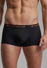 Boxers noirs en matière extensible avec une coupe ajustée. La ceinture présente "TOM TAILOR" en lettres orange.