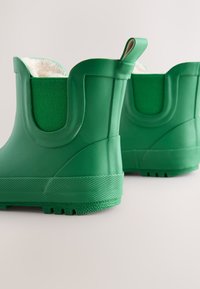 Stivali di gomma verdi con esterno testurizzato, pannelli elastici laterali e fodera morbida. Presentano un tallone rinforzato e una suola scolpita per una migliore trazione.