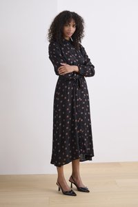 Schwarzes langärmliges Kleid mit runden braunen Punkten, mit einem Kragen, Knopfverschluss und einem Kordelzugbund für eine angepasste Passform.