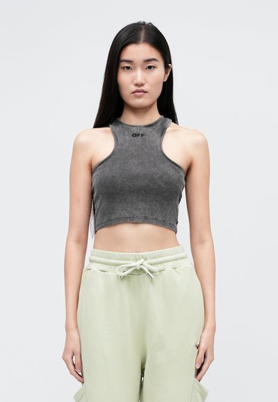 Szary prążkowany crop top bez rękawów z wysokim dekoltem, ozdobiony małym logo na środku, w połączeniu z jas Зелеными spodniami dresowymi.