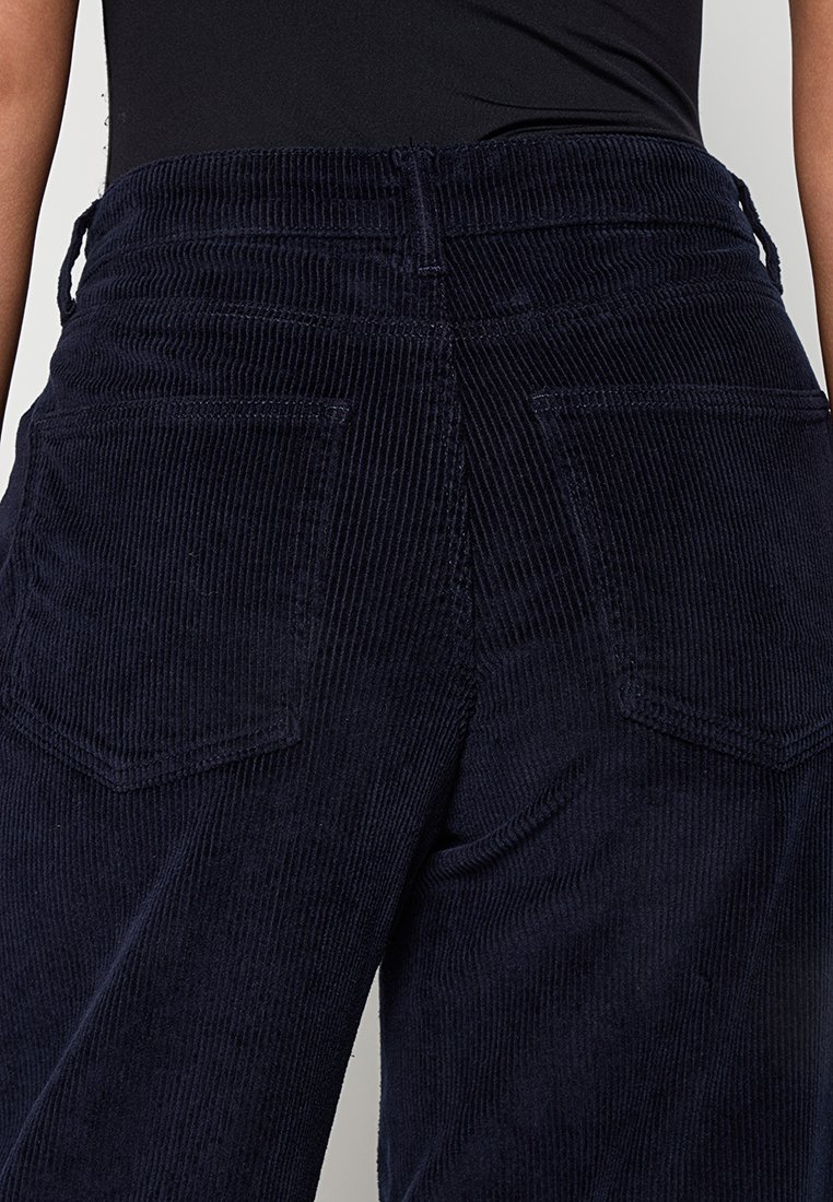 Navy Cordhose mit hoher Taille, weitem Bein und zwei Gesäßtaschen mit gerippter Textur.