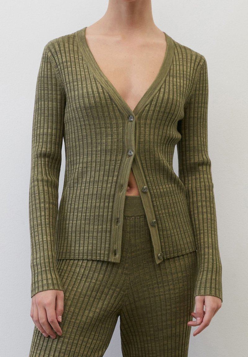 Olivkowy, prążkowany kardigan z głębokim dekoltem w kształcie V, długimi dopasowanymi rękawami i sześcioma guzikami z przodu. Wykonany z teksturowanej dzianiny.