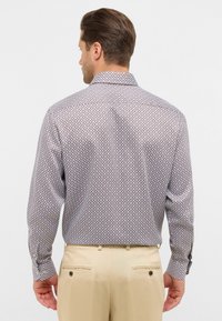 Camicia con bottoni in tessuto leggero, con un motivo geometrico in rosso e blu. Maniche lunghe con polsini abbottonati, design del colletto classico.