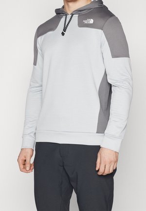 Vaaleanharmaa huppari tummanharmailla yksityiskohdilla, teksturoidusta kankaasta, säädettävä kaulanauha ja logo vasemmassa rinnassa. Tiimalasimallinen muotoilu, pitkät hihat.