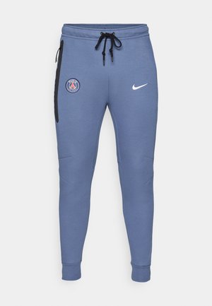 Blauwe sweatpants van zacht materiaal, met een Parijse embleem op de linkerdij en een wit Nike-log aan de rechterheup. Elastische boorden.