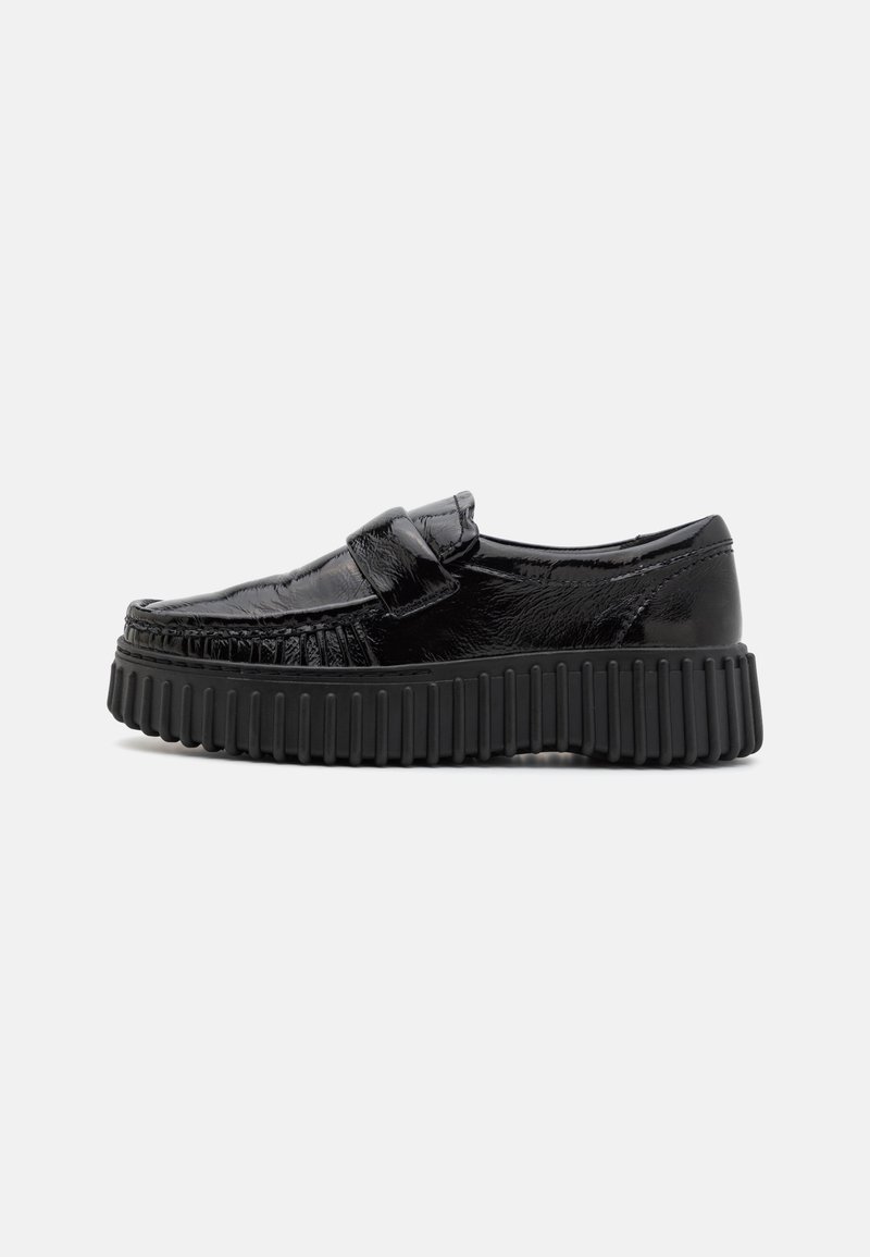 Zwarte loafers met een glanzende afwerking, voorzien van een ronde neus, geribbeld zwart zool en een band over de bovenkant voor extra detail.