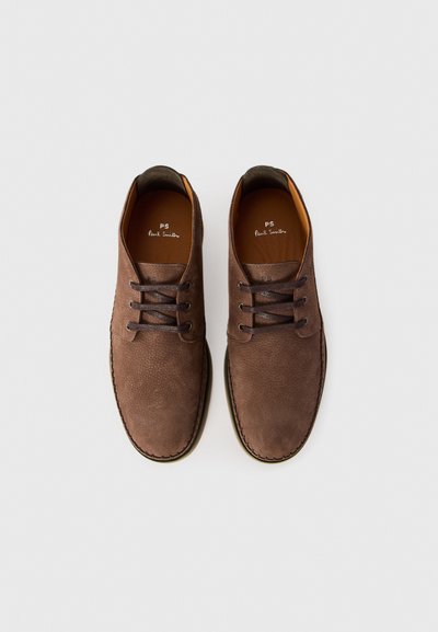 Scarpe in suede marrone con una superficie liscia, punta rotonda e quattro asole per i lacci. L'interno è foderato in beige e presenta un logo stampato in bianco.