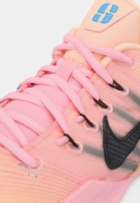 Ροζ αθλητικό παπούτσι με υφασμάτινο επάνω μέρος σε υφή, γκρι ρίγες, μαύρο λογότυπο Nike και επίπεδα κορδόνια. Ορατή μαλακή επένδυση στη φτέρνα.