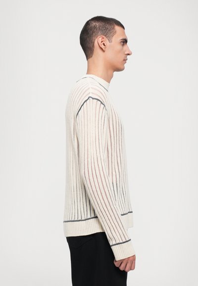 Ribbed knit sweater in cream with contrasting vertical stripes in light brown and navy. Features a high neck and fitted cuffs.