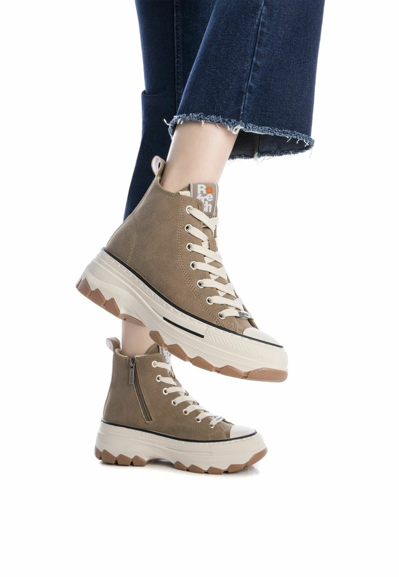 Sneakers alta marroni con tessuto testurizzato, suola bianca a contrasto e battistrada a zig zag. Presentano una cerniera laterale e un design con lacci.