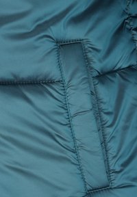 Tkanina kurtki puchowej w kolorze morskim, z pikowaną teksturą i boczną kieszenią. Gładkie, błyszczące wykończenie z subtelnymi szwami.