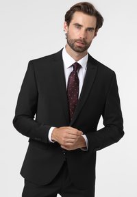 Schwarze Anzugjacke mit passender Hose, weißes Dress-Shirt und burgunderrote Krawatte mit weißen Punkten. Slim Fit und Schalkragen.