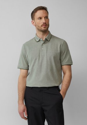 Lichtgroene polo met korte mouwen, van textuurstof, met een knoopsluiting en een contrasterende kraag, gecombineerd met donkere broek.