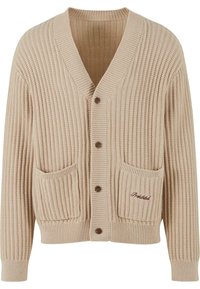 Cardigan tricotat cu nervuri, de culoare bej, cu decolteu în V, închidere cu nasturi pe față, două buzunare patch și detalii brodate pe buzunarul din stânga.