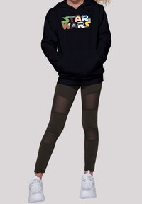 Sudadera negra con gráfico de "Star Wars" en colores vibrantes. Leggings verde oliva con paneles de malla y zapatillas blancas. Diseño simple y deportivo.