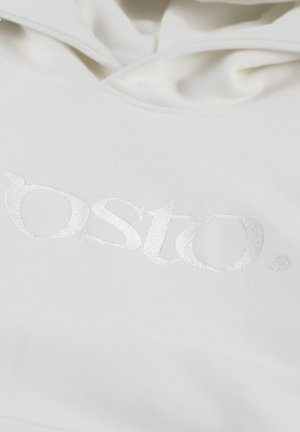 Biała bluza z kapturem, charakteryzująca się miękką teksturą oraz wyraźnym, odblaskowym wytłoczonym logo na środku. Projekt jest prosty i elegancki.