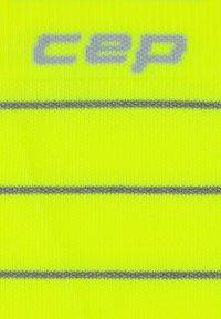 Fluoreszierende gelbe Kompressionssocken mit grauen Streifen und dem eingewobenen "cep"-Logo. Weicher, dehnbarer Stoff.