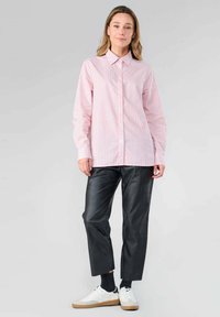 Light pink button-up shirt with thin vertical stripes in red and blue, paired with black leather pants and white sneakers.