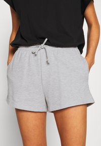 Světlé šedé šortky z bavlněné směsi s elastickým pasem a stahovací šňůrkou. Obsahují dvě boční kapsy a volný střih. Hladká textura.