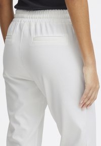White, relaxed-fit sweatpants with an elastic waistband and two back pockets. Smooth texture and minimal design details.