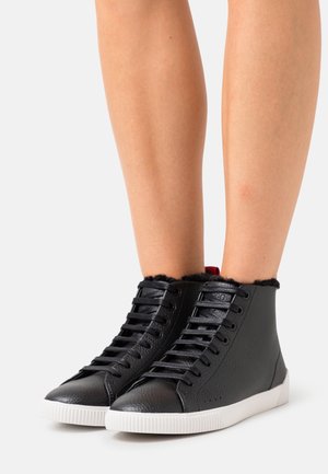 Black high-top sneakers with leather exterior, white rubber sole, round toe, and fuzzy black trim at the collar; features black laces.