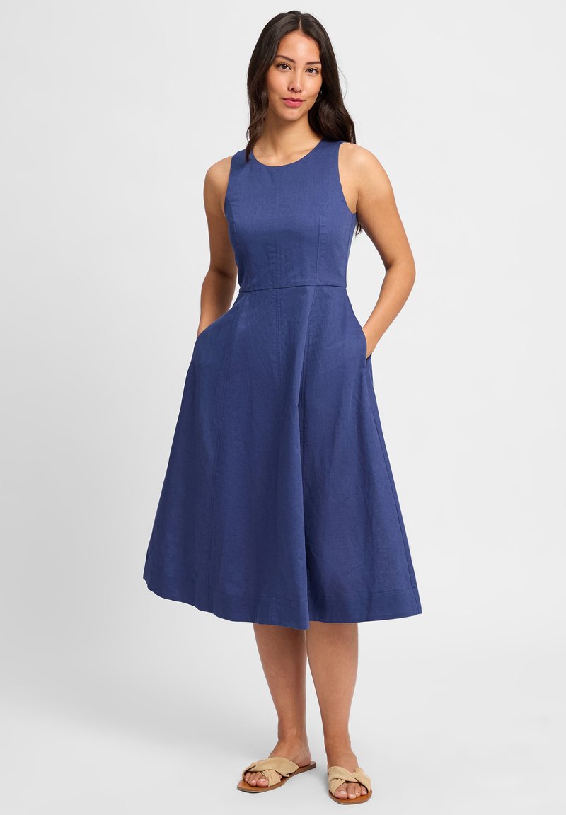 Marineblauw mouwloos jurkje van een gestructureerde stof, met een aansluitend lijfje, een uitlopende rok en zijzakken.