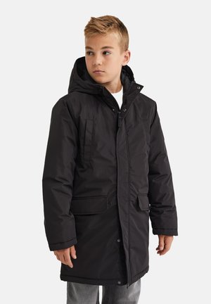 Parka noir imperméable avec capuche, dotée de fermetures éclair et de boutons-pression, de deux poches avant et d'une texture matelassée. Manches longues avec poignets.