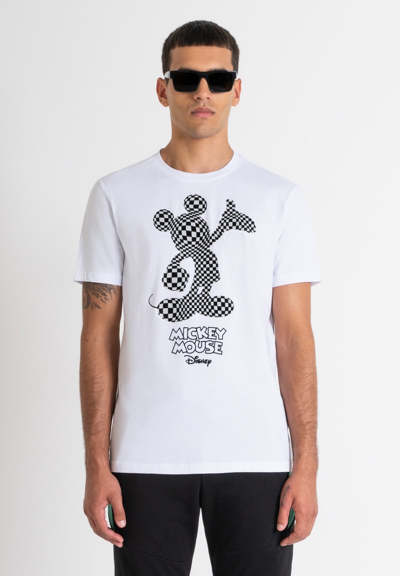 Camiseta de algodón blanca con un gráfico de Mickey Mouse en blanco y negro con un diseño de cuadro. Incluye el texto "MICKEY MOUSE" en una fuente en negrita.