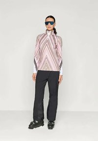 Zipperes rózsaszín és bézs csíkozott felső magas gallérral, fekete nadrággal párosítva. Texturált anyag, sportos dizájn és elegáns fekete csizmák.