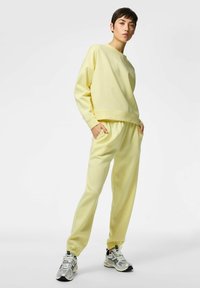 Sudadera amarilla y pantalones jogger a juego hechos de tela suave, con un ajuste relajado, puños acanalados y cintura elástica.